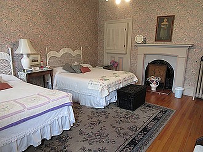Spacious guest room with two beds and a period fireplace
